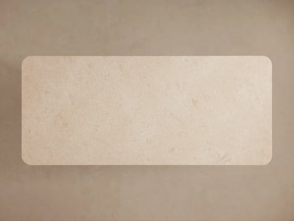 Close-up of Caden Dining Table's sand-colored stone top with rounded double-edge detail and light oak veneer base.
