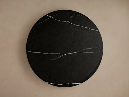 Close-up of Caden Round Dining Table with a black marble top featuring white veins, resting on a dark brown walnut wood base.