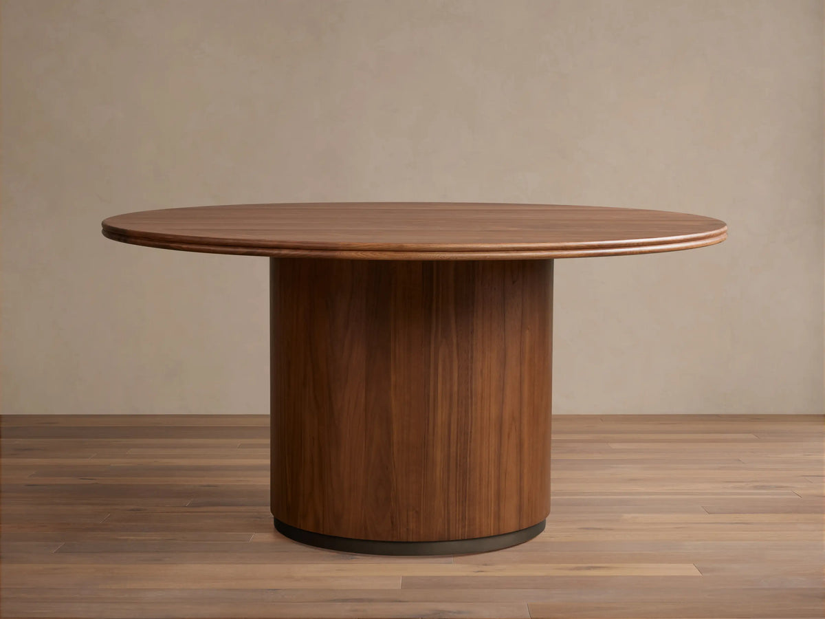 Caden Round Wood Dining Table, dark walnut finish, round top & thick cylindrical base on wood floor.