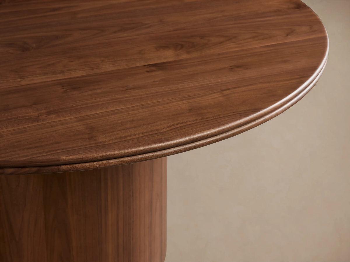 Caden Round Wood Dining Table, dark walnut finish, round top & thick cylindrical base on wood floor.