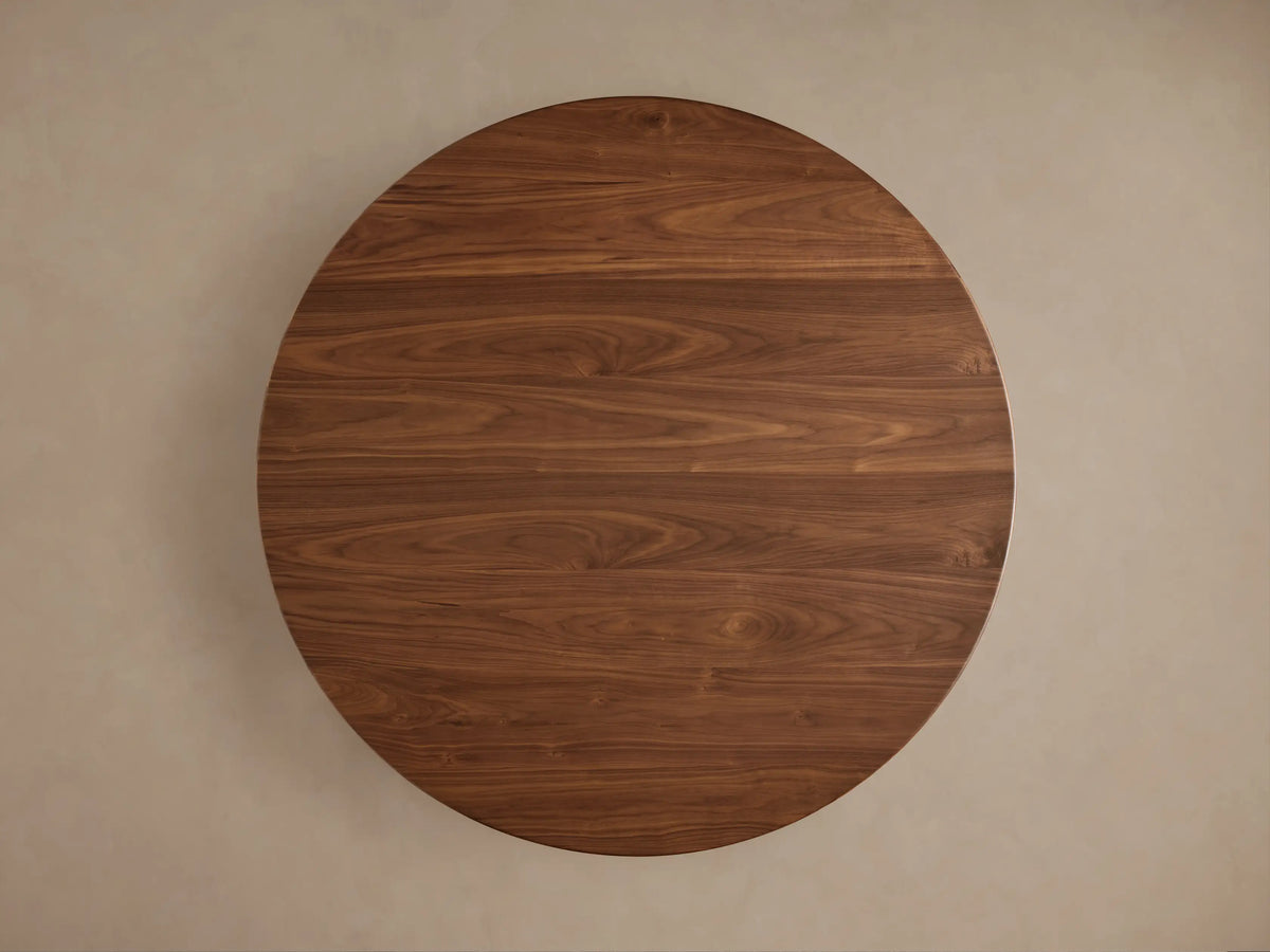 Close-up of Caden Round Wood Dining Table. Dark walnut finish with visible wood grain on round top and cylindrical base.