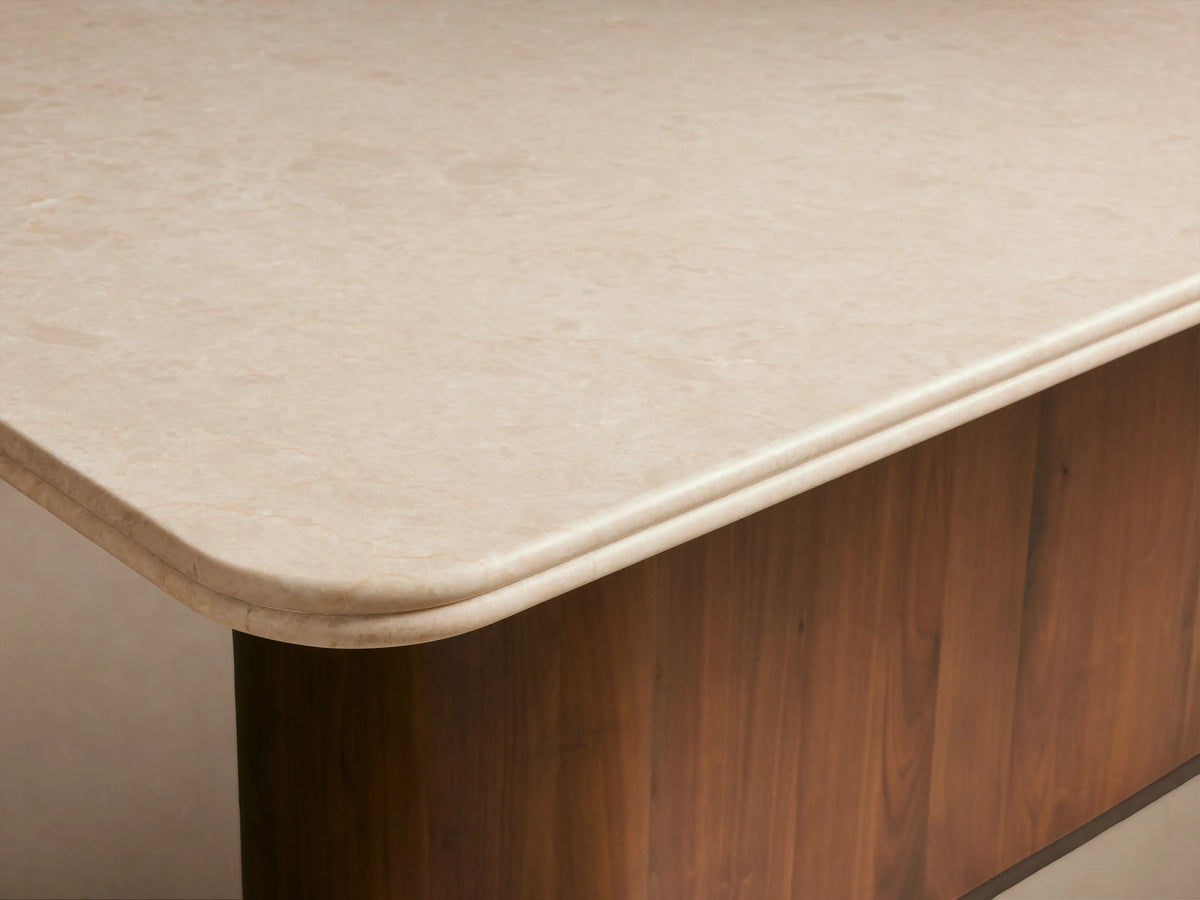 Caden Dining Table featuring a light rectangular stone top and a dark, curved walnut wood base.