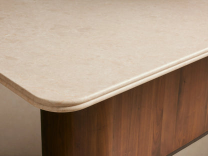 Caden Dining Table featuring a light rectangular stone top and a dark, curved walnut wood base.