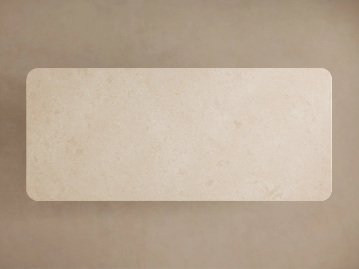 Caden Dining Table close-up showing creamy stone top with a rounded, double-bead edge over a dark walnut wood base.