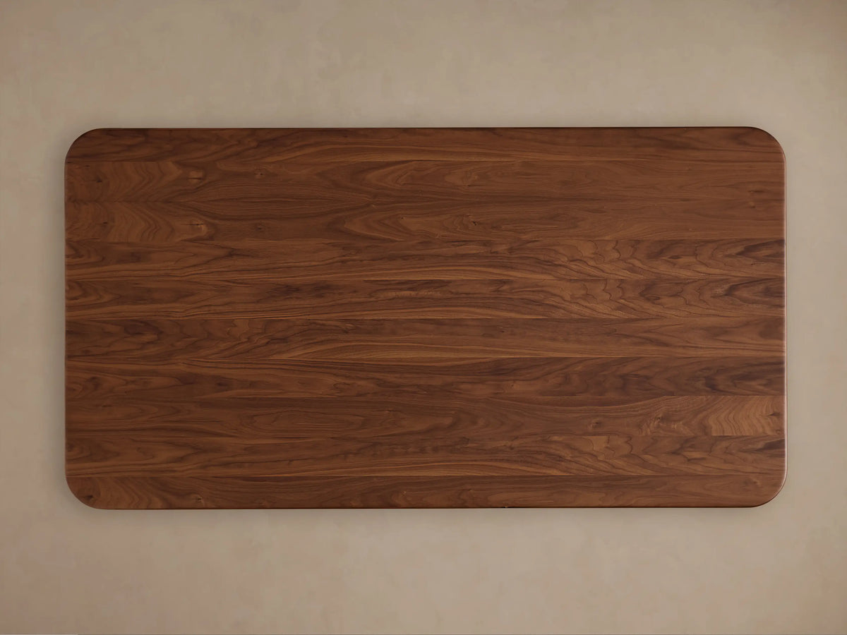 Caden Wood Dining Table: Close-up of its rounded, dark walnut wood top corner, showing rich grain and a smooth, sculpted edge.