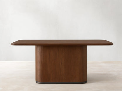 Caden Wood Dining Table: Rectangular top with rounded corners, solid pedestal base, rich walnut wood finish.