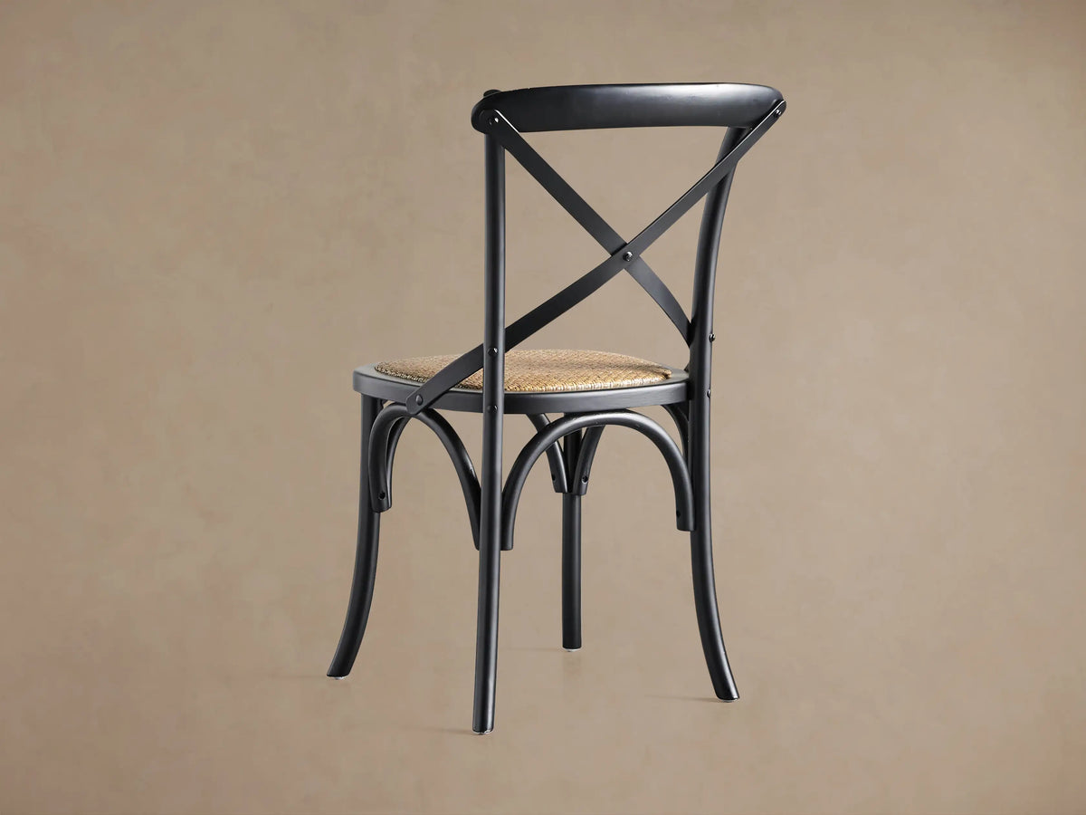 Close-up of a black Cadence Dining Chair's curved solid birch wood top rail and X-stretcher back detail.