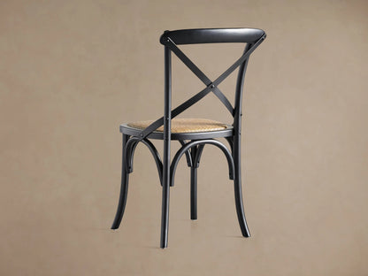 Close-up of a black Cadence Dining Chair's curved solid birch wood top rail and X-stretcher back detail.