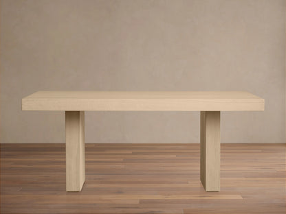 Calvin Dining Table: light oak rectangular table with two thick pedestal legs, natural wood grain, centered on wood floor.