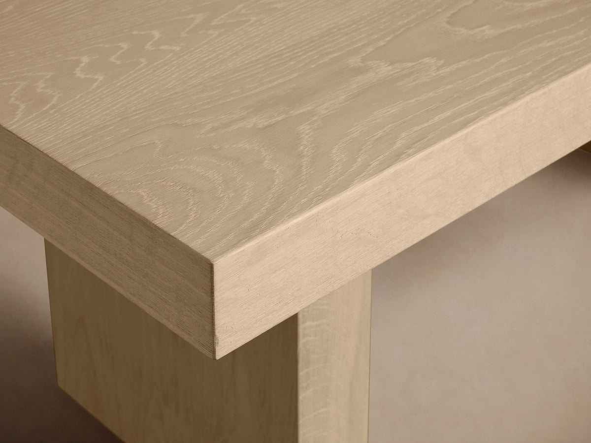 Calvin Dining Table: light oak rectangular table with two thick pedestal legs, natural wood grain, centered on wood floor.