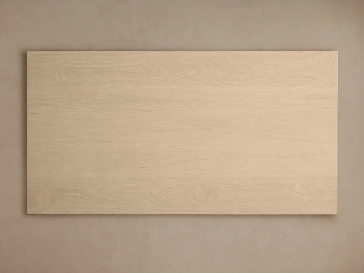Calvin Dining Table: light-colored oak veneer, rectangular top, two chunky pedestal legs, angled view.