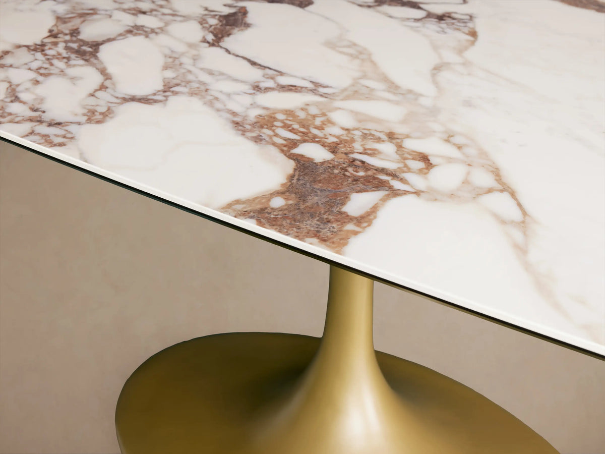 Vincenza Dining Table with a rectangular ceramic top featuring calacatta marble pattern, supported by a gold steel pedestal base.