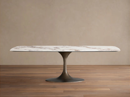 Vincenza Dining Table with Launette Base, ceramic top with calacatta marble design, steel base, on wooden floor.