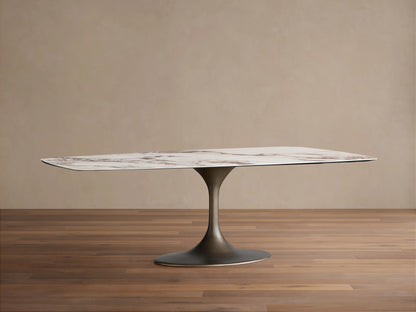 Vincenza Dining Table with Launette Base, ceramic top with calacatta marble design, steel base, on wooden floor.