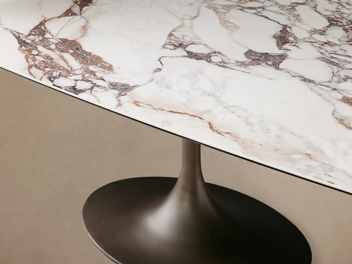 Vincenza Dining Table with calacatta marble pattern ceramic top, steel launette base on wooden floor.