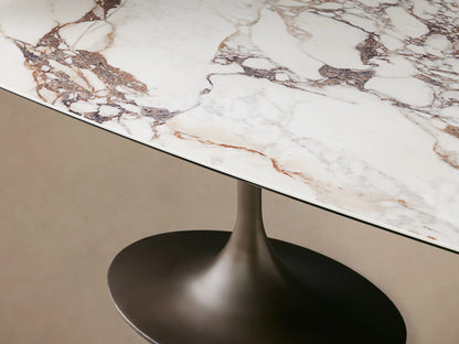 Vincenza Dining Table with calacatta marble pattern ceramic top, steel launette base on wooden floor.