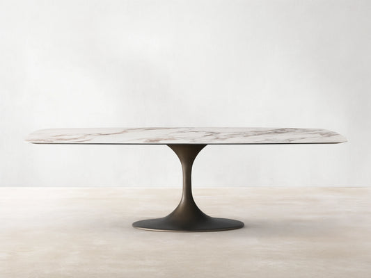 Vincenza Dining Table with Launette Base, ceramic top with calacatta marble design, steel base, on wooden floor.