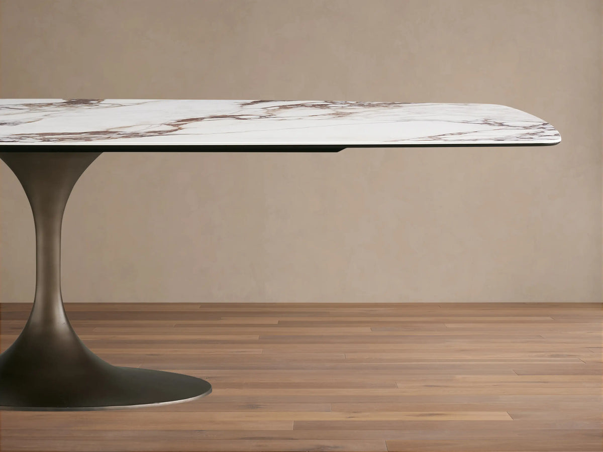 Vincenza Dining Table with a ceramic tabletop featuring a calacatta marble pattern, supported by a sleek steel base.