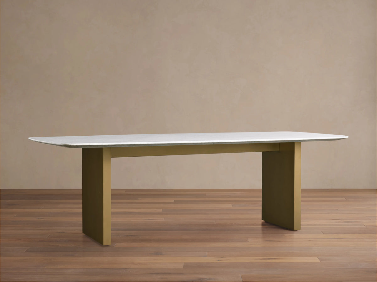 Saint Germain Stone Dining Table with white marble top and olive brown base on wood floor, minimalistic setting.