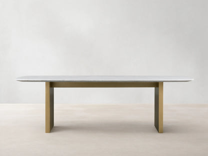 Saint Germain Stone Dining Table with white marble top and olive brown base on wood floor, minimalistic setting.