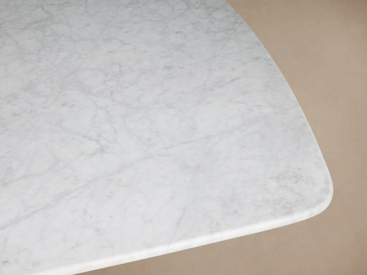 Saint Germain dining table with an elongated Carrara marble top and a sturdy dark wood base on wooden flooring.