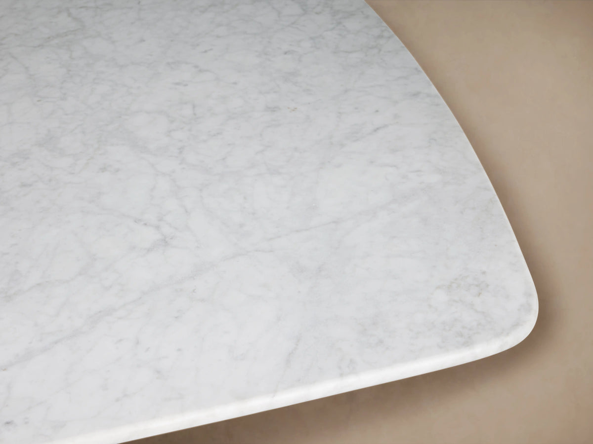 Saint Germain Dining Table with rectangular white marble top, dark wooden base, set in an empty, minimalist room.