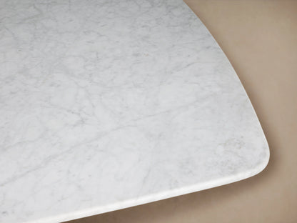 Saint Germain Dining Table with rectangular white marble top, dark wooden base, set in an empty, minimalist room.