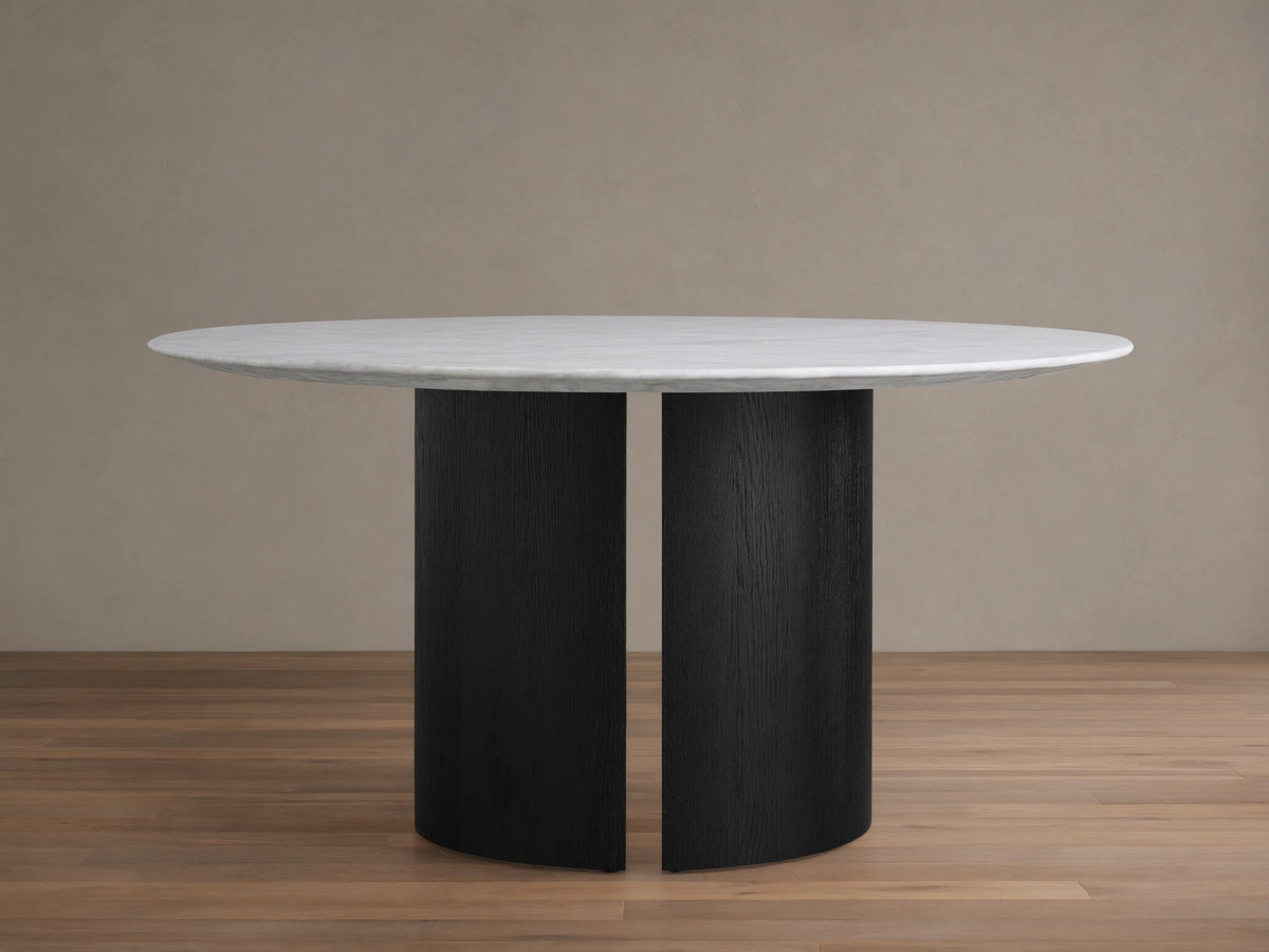 Saint Germain Round Stone Dining Table: White marble top resting on a black wood Dauphine base with two curved vertical segments.