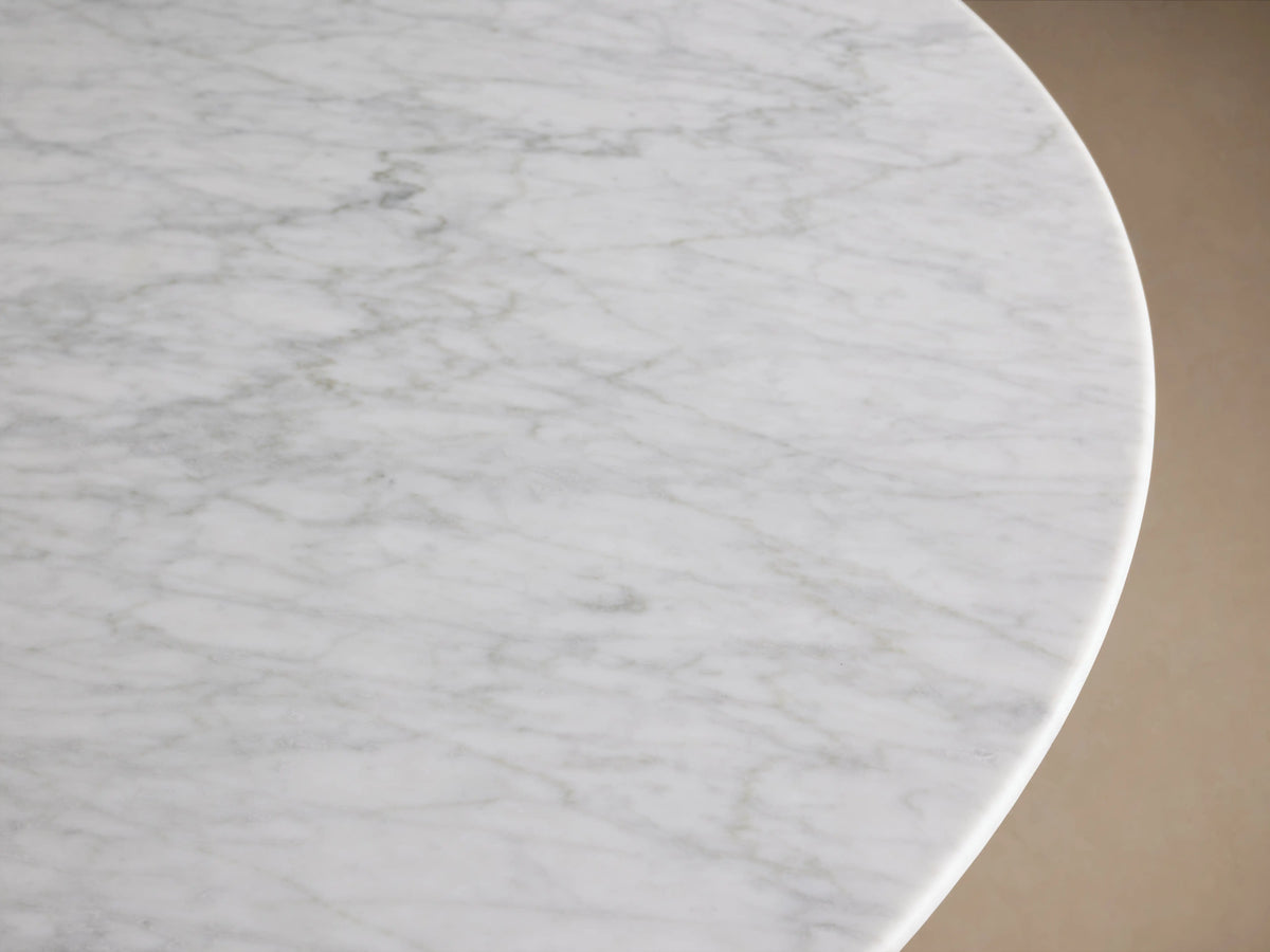 Close-up of the Saint Germain Round Dining Table's white Carrara marble tabletop, showing gray natural veining and smooth surface.