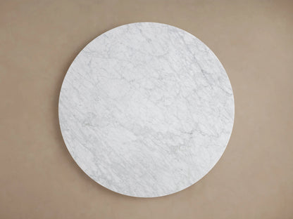 Saint Germain Round Stone Dining Table: White marble top resting on a black wood Dauphine base with two curved vertical segments.