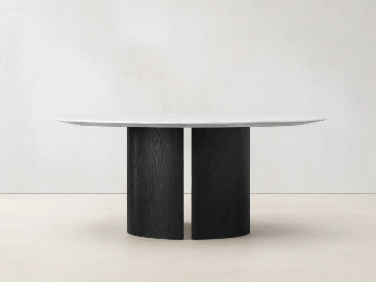 Saint Germain Round Stone Dining Table: White marble top resting on a black wood Dauphine base with two curved vertical segments.