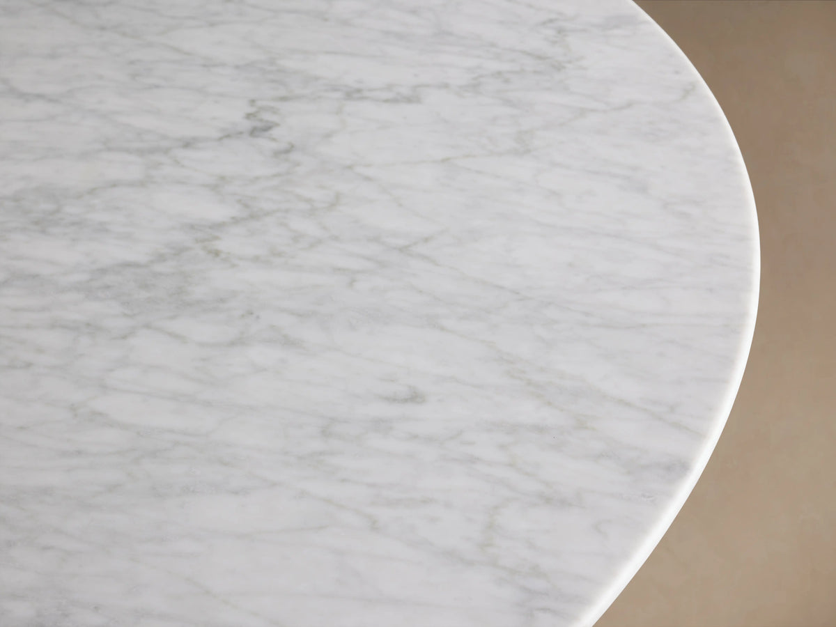 Round Carrara marble tabletop of the Saint Germain Dining Table, showing natural veining and subtle color variations, viewed from above.