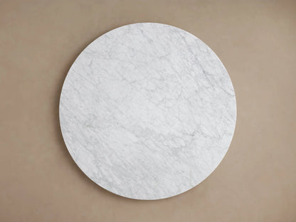 Round Saint Germain Dining Table with white Carrara marble top, showcasing natural veining and smooth edges, set against a neutral background.