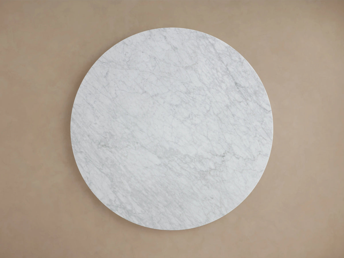Round tabletop of the Saint Germain Dining Table in light gray Carrara marble with subtle veining, showcasing smooth polished edge.
