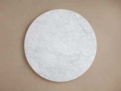 Round dining table with a smooth Carrara marble top showcasing natural veining and variations in light gray and white tones.