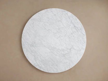 Round tabletop made from Carrara marble with visible gray veining and subtle white tones against a beige background.
