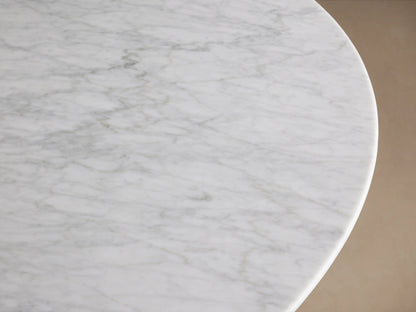 Round tabletop of the Saint Germain Dining Table made of Carrara marble, displaying gray veining on a white surface.