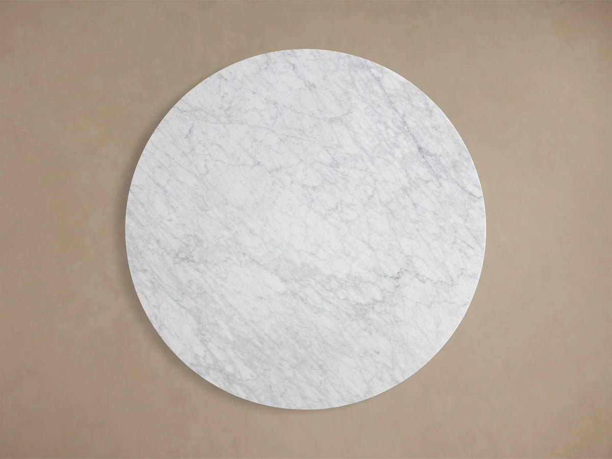 Close-up of the white Carrara marble surface of the Saint Germain Round Stone Dining Table with Rennes Base in Metal, showing grey veining.