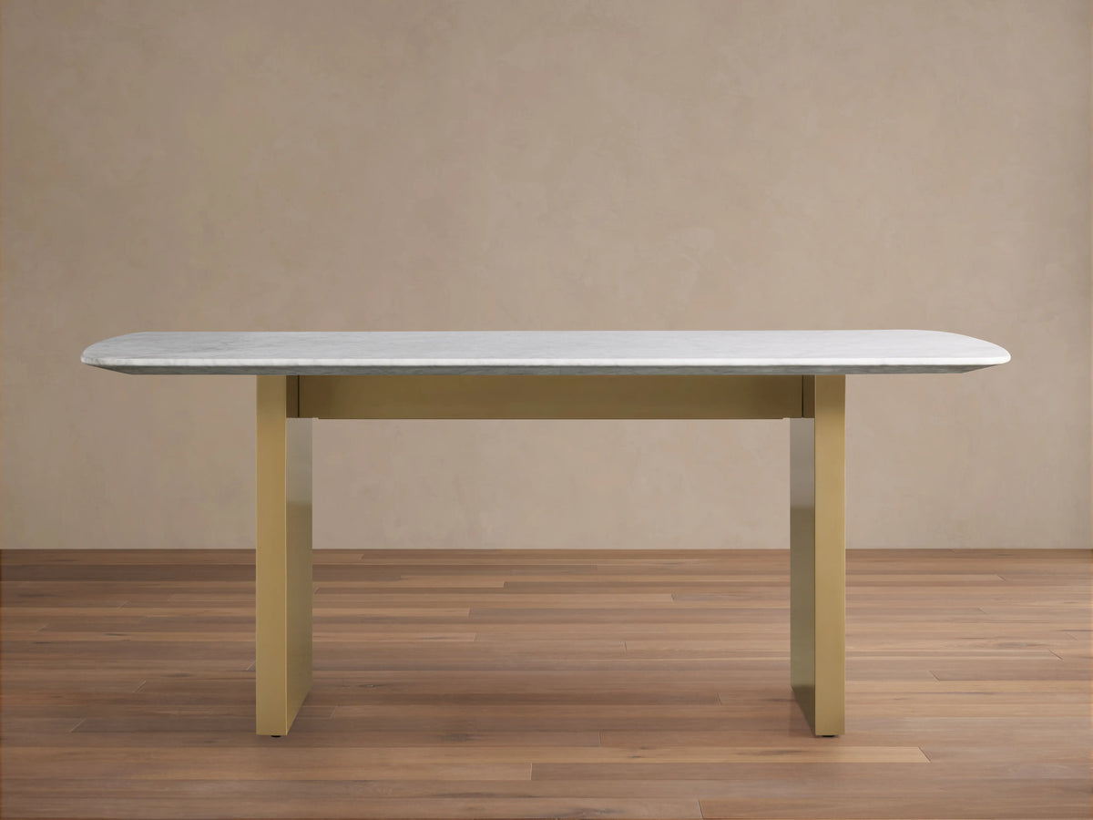 Saint Germain Stone Dining Table with a smooth white Carrara marble top on a sturdy, rectangular antique brass base.