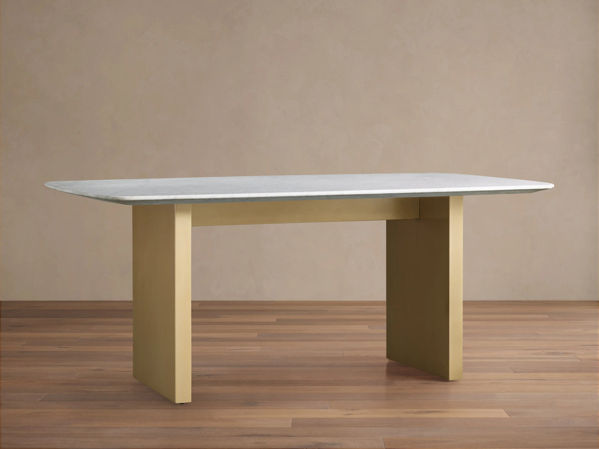 Saint Germain Stone Dining Table with a smooth white Carrara marble top on a sturdy, rectangular antique brass base.