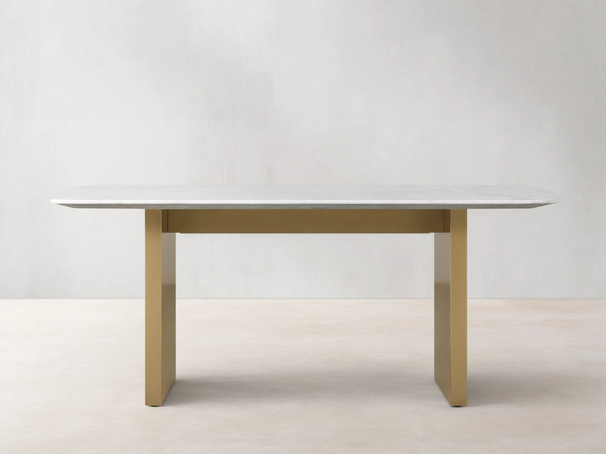 Saint Germain Stone Dining Table with a smooth white Carrara marble top on a sturdy, rectangular antique brass base.
