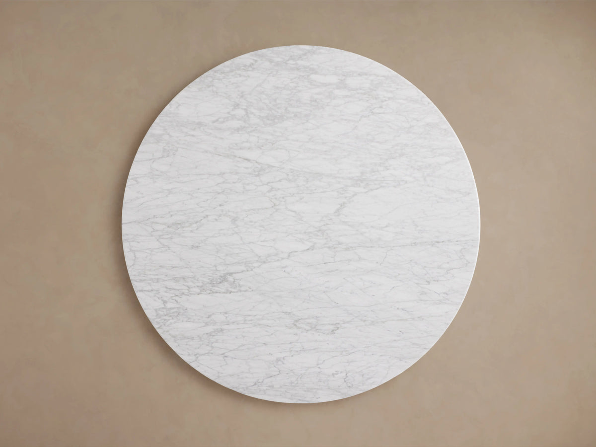 Round tabletop made of light gray Carrara marble with natural veining, smooth surface, and polished edge, viewed from above.