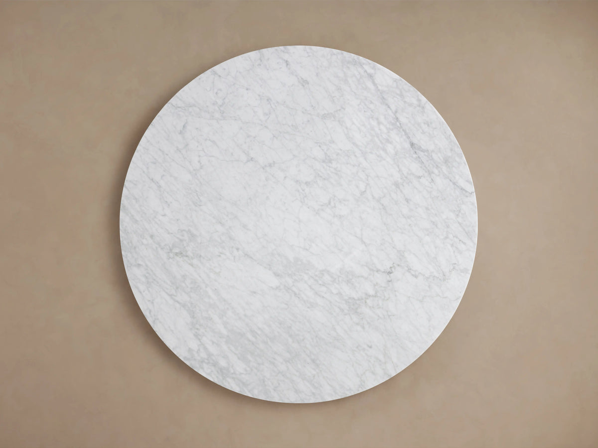 Round tabletop of the Saint Germain Dining Table made from Carrara marble, displaying natural veining and a smooth edge.