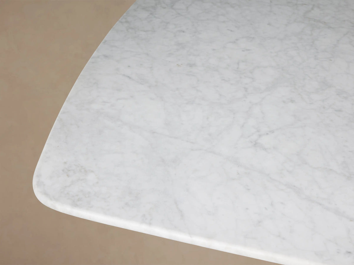 Front view of the white Carrara marble Saint Germain 96" Stone Dining Table with an Antique Bronze Metal Clement Base.