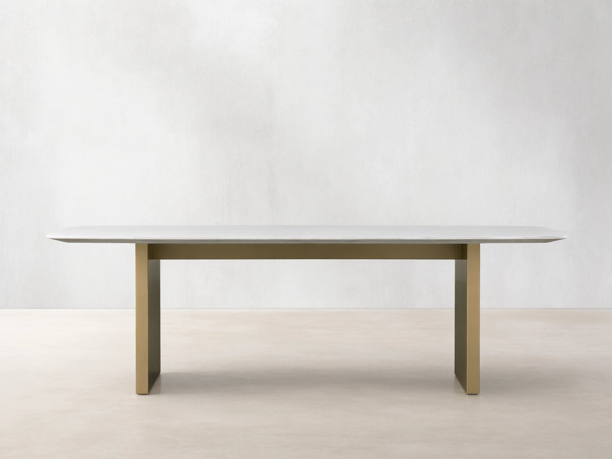 Front view of the Saint Germain 96" Stone Dining Table with Metal Clement Base, white stone top and brass bases.