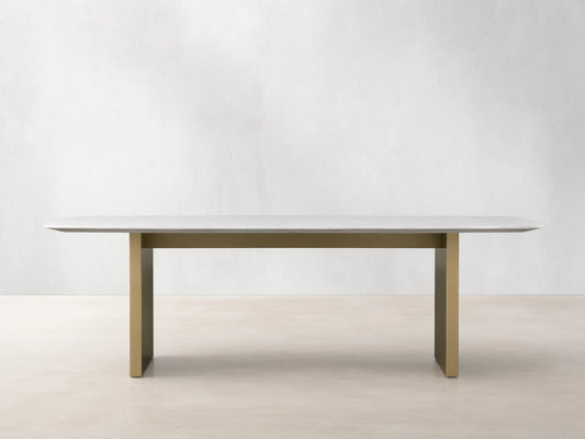 Front view of the Saint Germain 96" Stone Dining Table with Metal Clement Base, white stone top and brass bases.