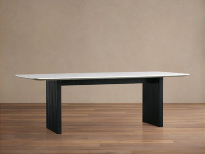 Saint Germain dining table with white Carrara marble top and black wood base on a wooden floor, beige wall background.