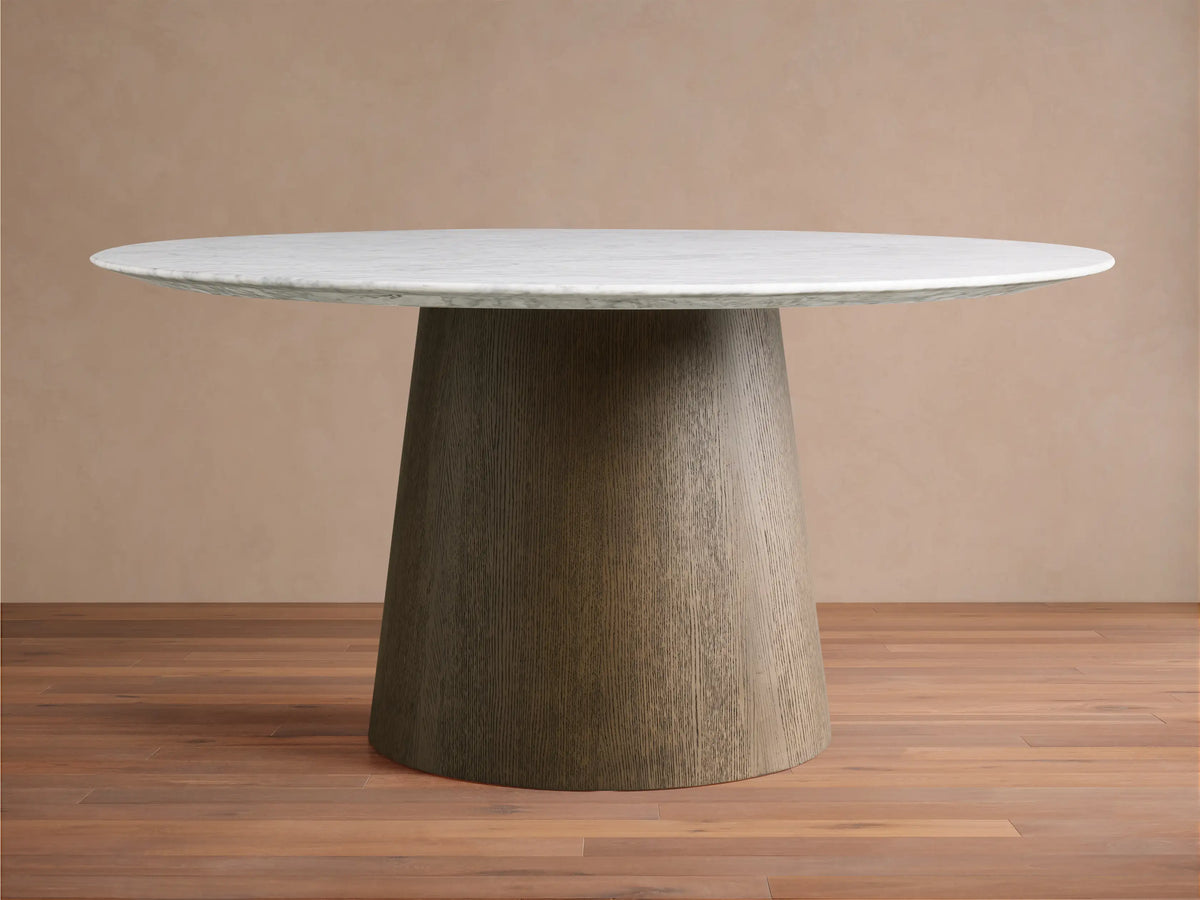 Round dining table with a white Carrara marble top and a conical wooden base made of plywood and oak veneers, on a wooden floor.
