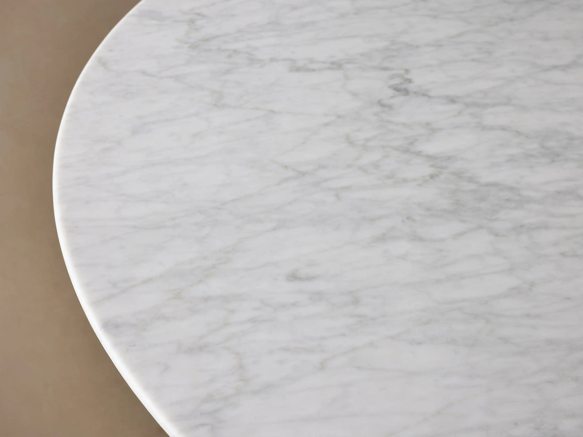 Round dining table with a Carrara marble top in white, featuring subtle veining. The base is a black, cone-shaped structure made of plywood and oak veneers.