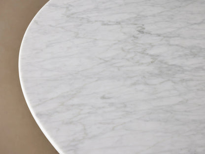 Round dining table with a Carrara marble top in white, featuring subtle veining. The base is a black, cone-shaped structure made of plywood and oak veneers.